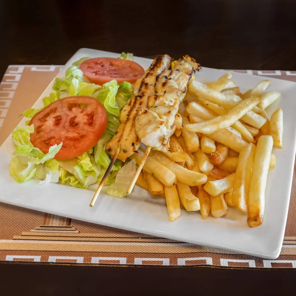 GRK Grill's chicken souvlaki skewers with french fries, lettuce, and tomato slices.